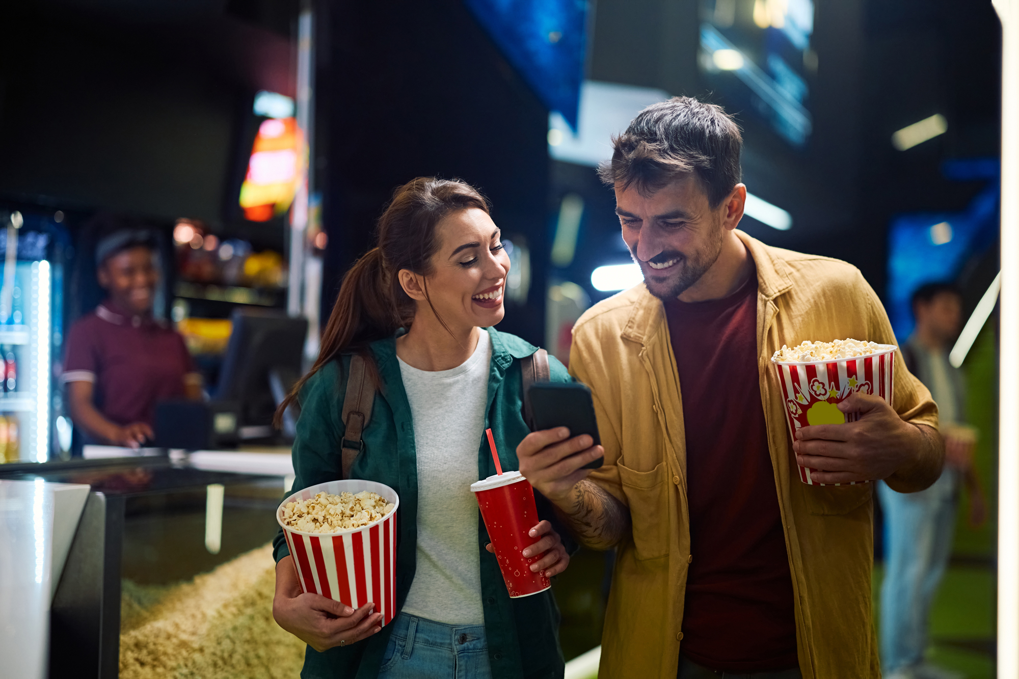 Couple checking phone in a cinema foyer