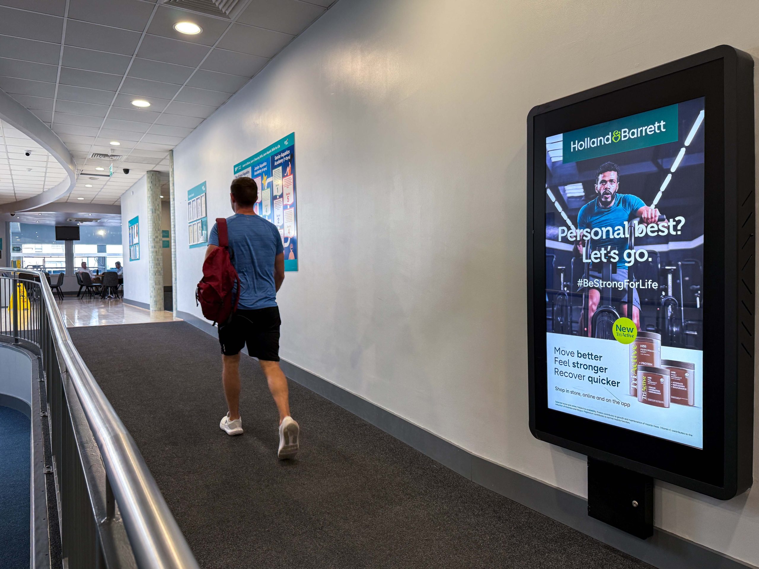 Man walking past DOOH in gym